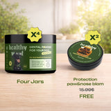Two jars of 'Healthy World' pet care products on a wooden surface with a blurred natural background.